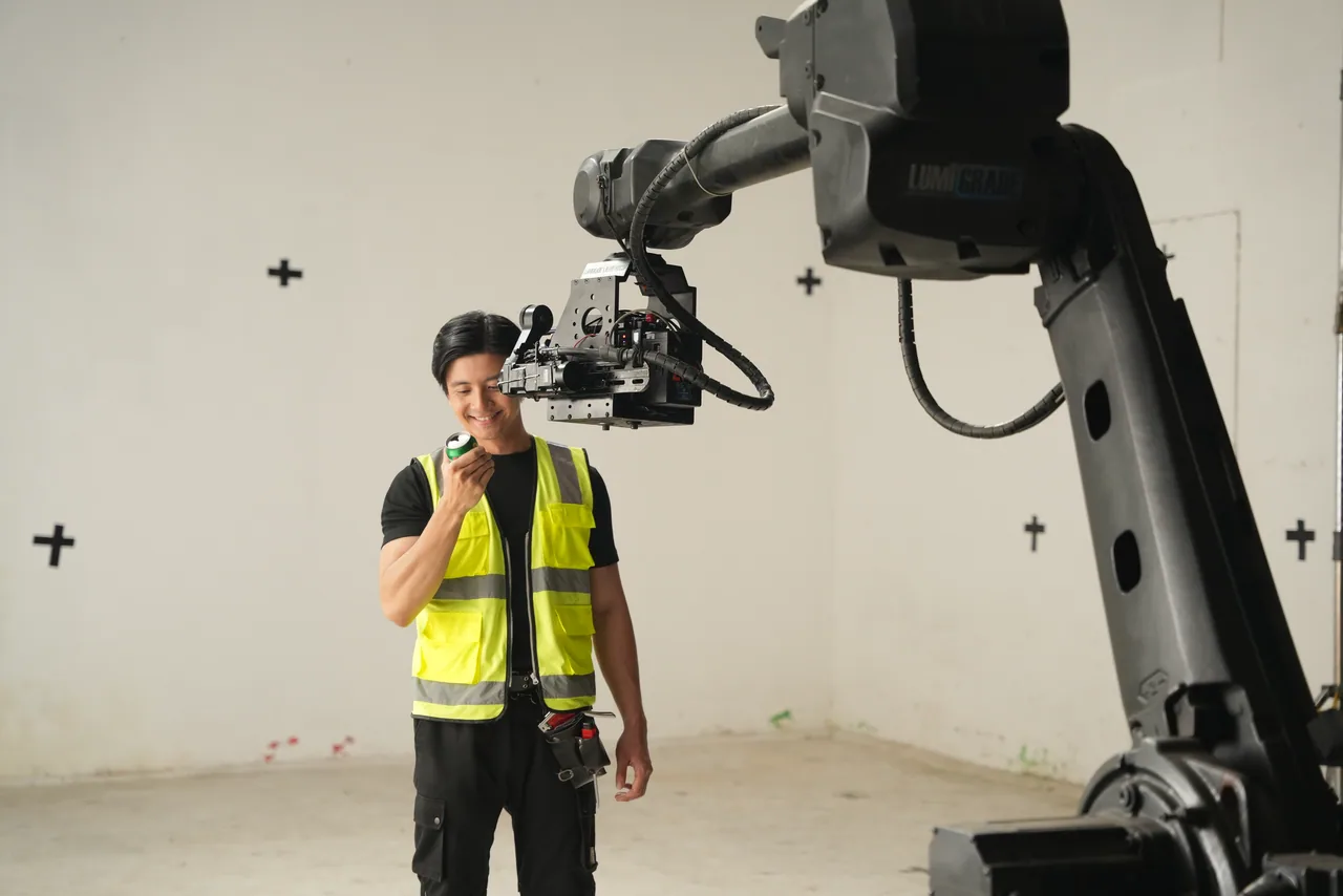 The camera head passing within inches of a crew member as the arm sweeps across the studio floor