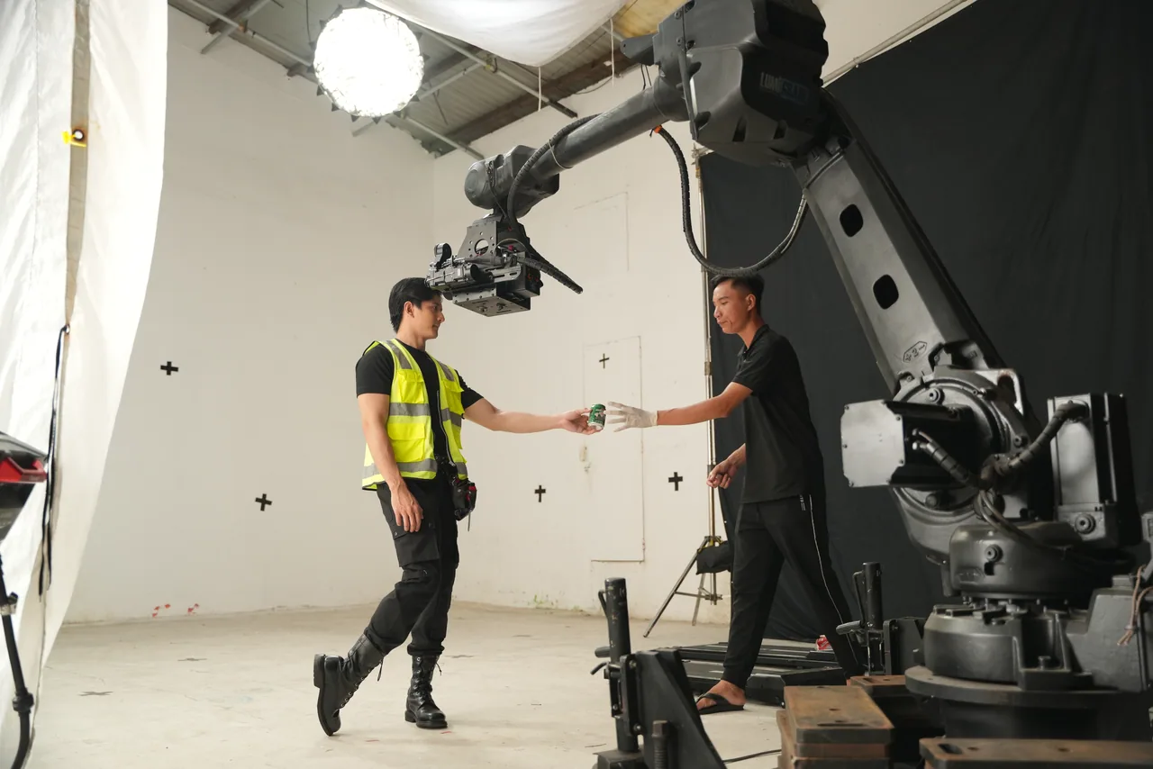 A crew member handing the next set-up across to the operator under the arm