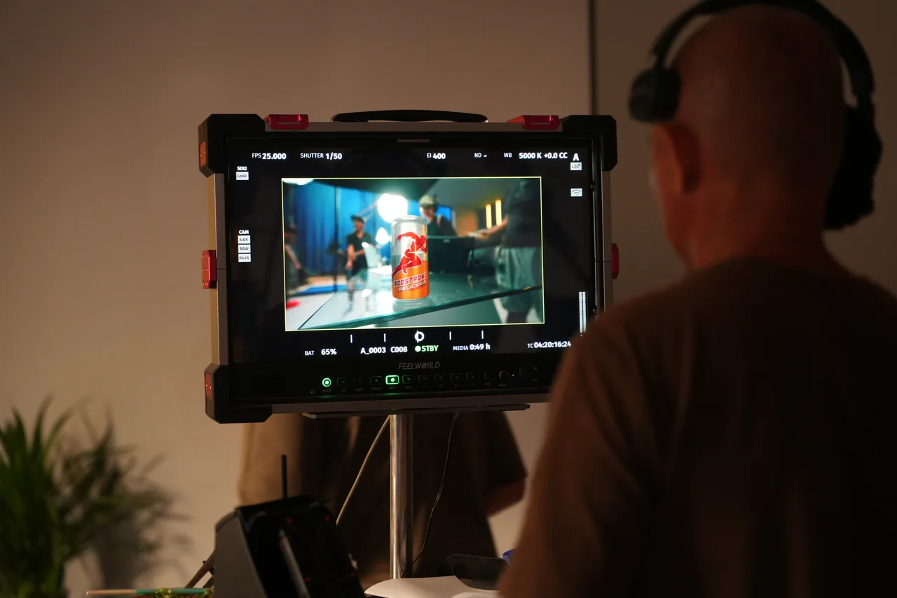 The product shot framed up on the monitor, the operator’s silhouette filling the dark foreground